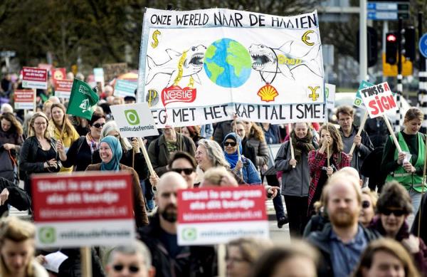 Miembros de seis organizaciones ecologistas holandesas se dirigen a entregar una citación judicial a la multinacional petrolera Shell.