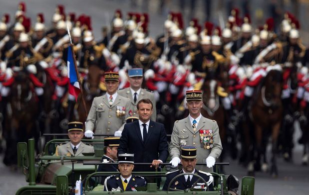 El presidente francés, Emmanuel Macron (c), a bordo del vehículo militar, flanqueado por la Guardia Repulblicana montada, asiste al desfile militar anual del Día de la Bastilla en la avenida de los Campos Elíseos en París, Francia, este 14 de julio. 