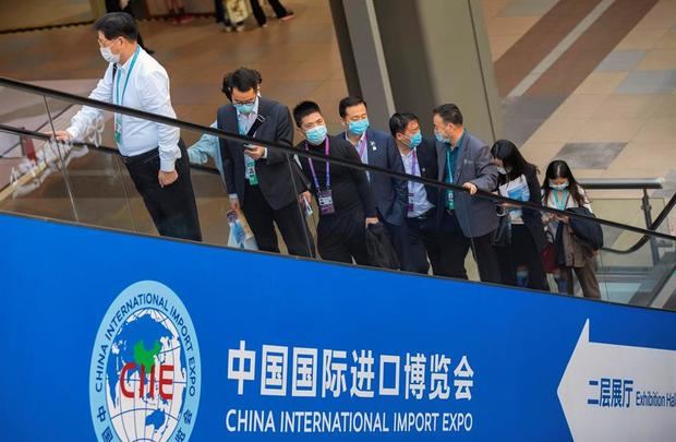 Numerosos visitantes montan en una escalera mecánica en la 3ª Exposición Internacional de Importación de China en Shanghai, China.