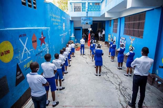 Estudiantes, usando tapabocas, participan de una ceremonia antes de retomar clases luego de cinco meses de cierre debido a la pandemia de coronavirus, este lunes, en Puerto Príncipe (Haití). 