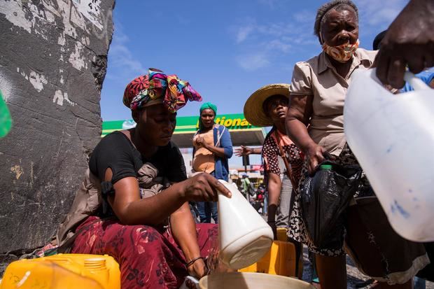 Una mujer vende gasolina en bidones y a un precio alto junto a las instalaciones de una estación de combustibles que no está prestando servicio al público hoy, en Puerto Príncipe, Haití.