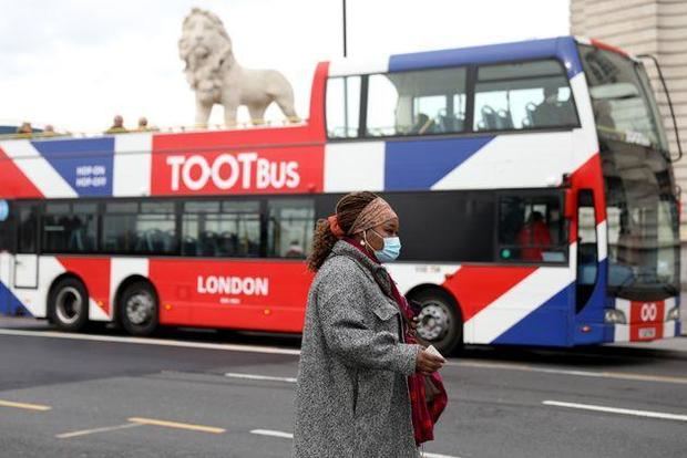 Una mujer camina con mascarilla por una calle de Londres.