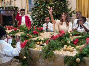 La primera dama de EE.UU., Melania Trump juega con un niño invitado a ver los adornos de la Casa Blanca lanzándole uno de los globos de la decoración.