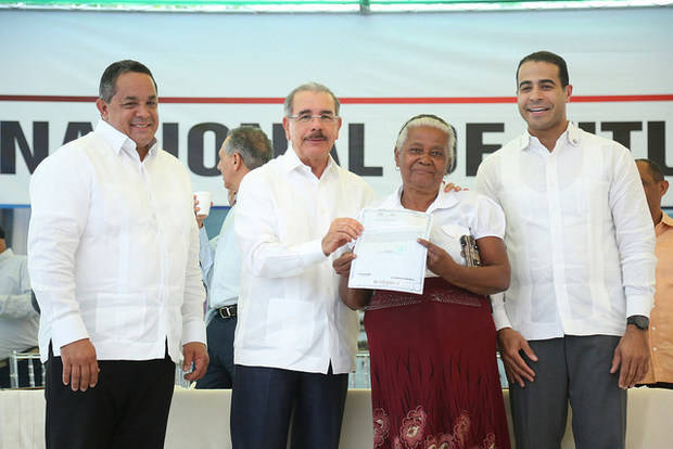 Presidente Medina entrega el titulo de propiedad a una beneficiada.
