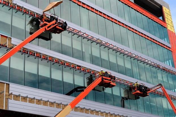 Trabajadores de la construcción realizan sus labores en la fachada de un edificio.