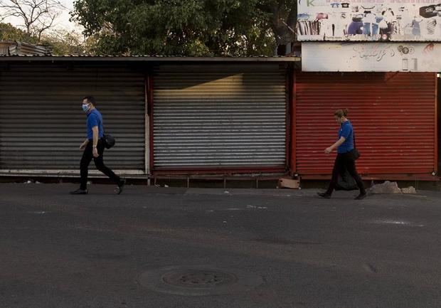 Dos personas caminan frente a varias tiendas cerradas en Managua, Nicaragua.