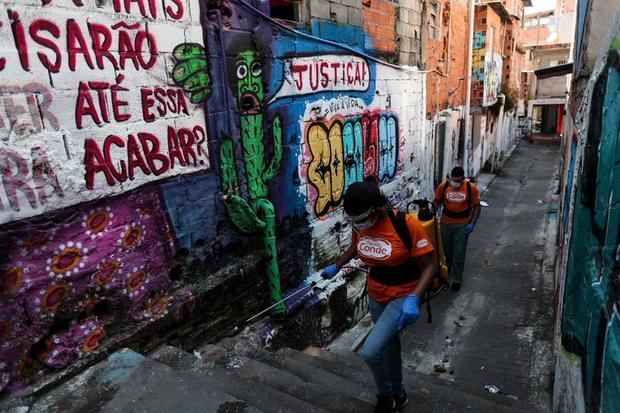 Funcionarios de la ciudad fueron registrados este jueves al desinfectar las calles de Paraisopolis, una de las mayores favelas de Sao Paulo (Brasil), gracias al uso de drones y pulverizadores con productos desinfectantes, para hacer frente a la pandemia del virus COVID-19. 