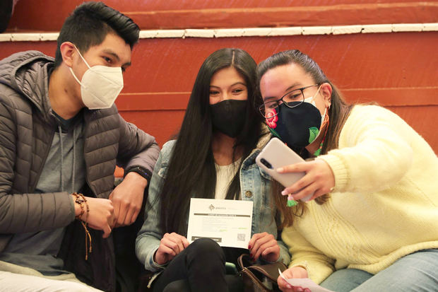 Jóvenes bolivianos posan para una foto con un certificado de vacunación contra la covid-19 hoy, en La Paz, Bolivia.