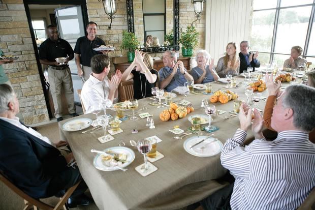 Fotografía cedida por The White House Historical Association donde aparece el cocinero Matthew Wendel (2i) mientras sostiene un plato antes los aplausos de la familia Bush durante una cena del Día de Acción de Gracias.