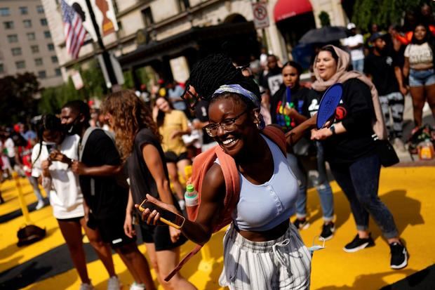 Personas celebran el 'Juneteenth', fecha que conmemora el fin de la esclavitud de la comunidad afroamericana, este 19 de junio de 2021, en la Black Lives Matter Plaza, de Washington.