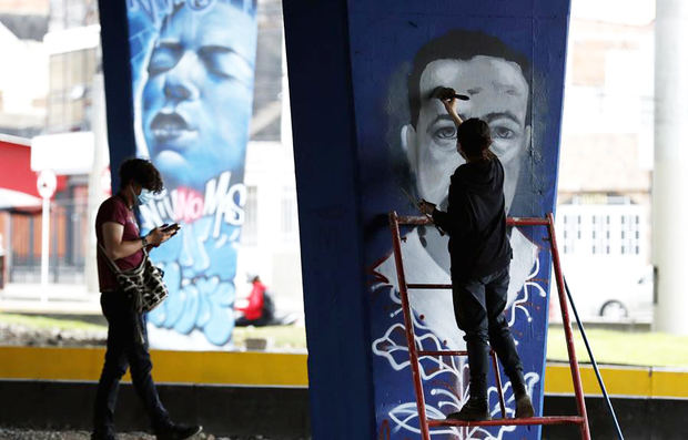 Artistas fueron registrados al pintar grafitis sobre las paredes de un puente, en memoria de las víctimas de la violencia policial, en Bogotá, Colombia.