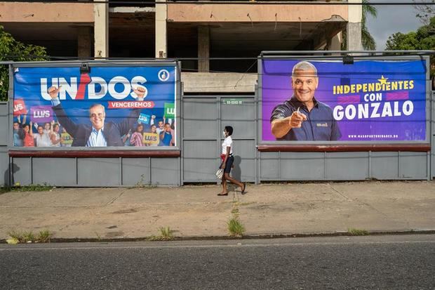 Una mujer con tapabocas es vista mientras camina cerca a vallas publicitarias de los candidatos presidenciales Luis Abinader y Gonzalo Castillo, este sábado en Santo Domingo.