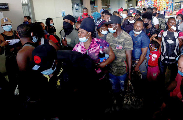 Migrantes haitianos esperan hoy para abordar un bus, en Cali, Colombia.