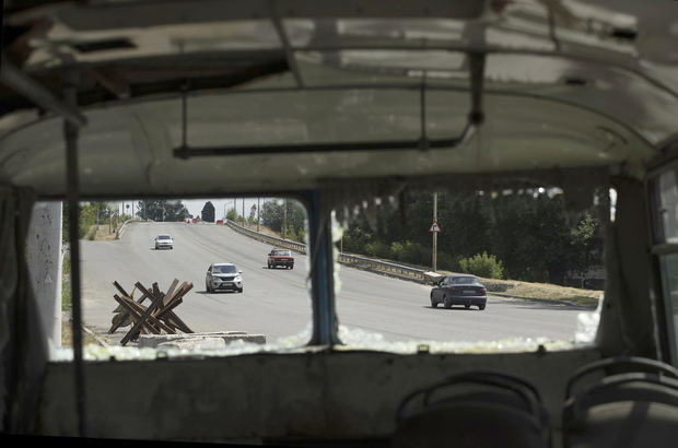 Automóviles pasan junto a un autobús destruido a un costado de la carretera que conduce a Dnipro, Ucrania.