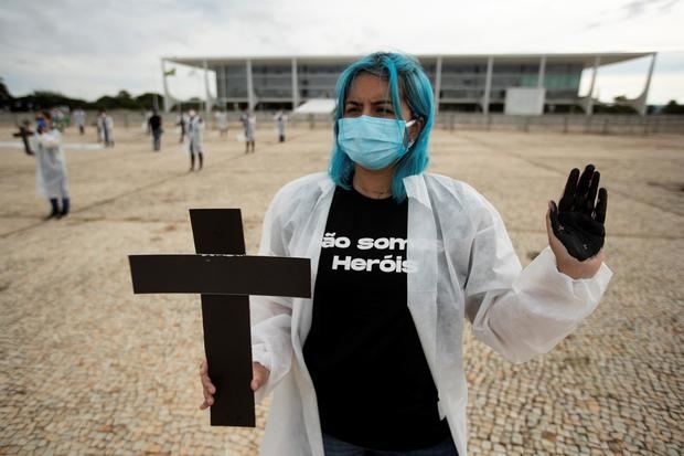 Una enfermera fue registrada este sábado al sostener una cruz, durante una protesta simbólica en honor a los profesionales de la salud y por las más de 400.000 muertes por el nuevo coronavirus en Brasil, frente al Palacio do Planalto, en Brasilia (Brasil).