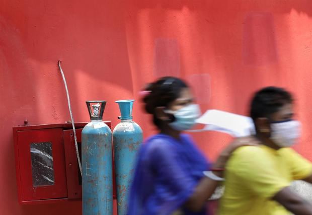 Una familia de un paciente con covid-19 pasa cerca de algunos cilindros de oxígeno en un hospital en Kolkata, India Oriental, el 28 de abril de 2021.