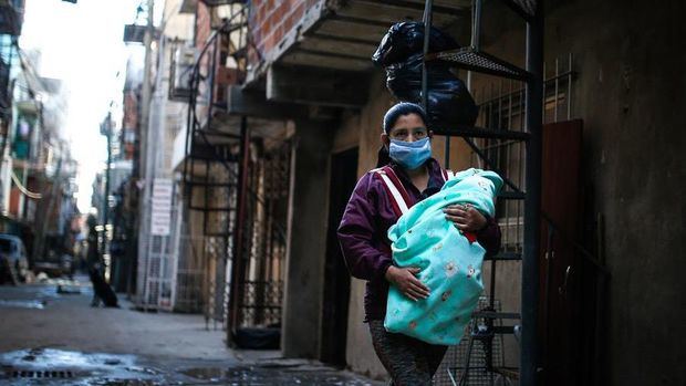En la imagen, una mujer con tapabocas lleva a su bebé por una calle de la Villa 31, en Buenos Aires (Argentina). 