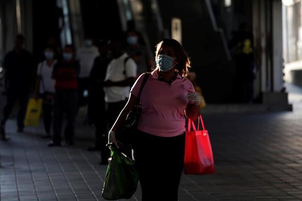 Una mujer usando un tapabocas camina, este lunes, por las calles en Ciudad de Panamá, Panamá.
