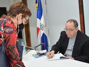 Monseñor Príamo Tejeda firma un ejemplar a Carmen de Armenteros.