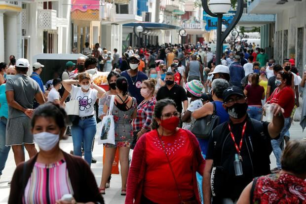 Varias personas con tapabocas caminan por una calle en La Habana.