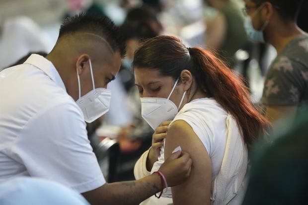 Fotografía de archivo del 24 de agosto de 2021 que muestra a un vacunador tras aplicar una dosis de la vacuna contra la covid-19 a una mujer, en Ciudad de México.