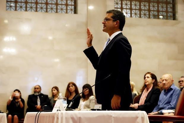 El abogado Pedro Pierluisi levanta su mano derecha durante una vista pública en la Cámara este viernes en San Juan, Puerto Rico, asumiendo así el cargo de nuevo gobernador.