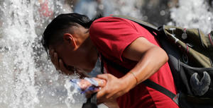 Un hombre se refresca en una fuente debido a las altas temperaturas.