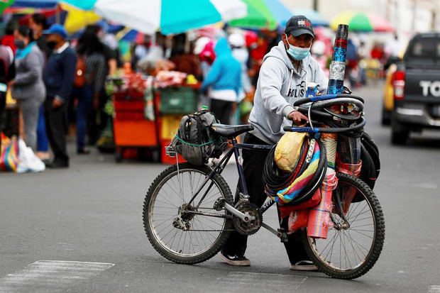 Un hombre empuja una bicicleta hoy en una calle cercana al mercado de Riobamba, Ecuador.