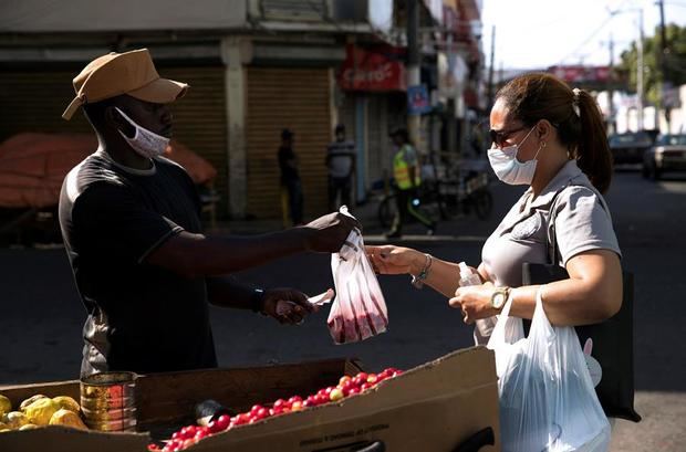 Un haitiano fue registrado al venderle una bolsa de cerezas a una mujer, durante el estado de emergencia para combatir la pandemia del virus COVID-19, en el barrio Pequeño Haití de Santo Domingo, Rep. Dominicana.