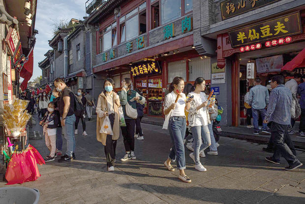 La gente pasa por las tiendas mientras visita la zona de Shichahai, en Pekín, China.