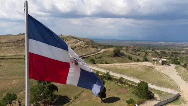 Fotografía aérea tomada con un dron que muestra la bandera de República Dominicana mientras ondea sobre la verja fronteriza entre República Dominicana y Haití, el 8 de mayo de 2021, en Comendador, colinas de Elías Piña, República Dominicana.