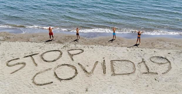 Una familia escribe la frase 'Stop Covid-19' en la arena de una playa de Nápoles, Italia, este sábado. 