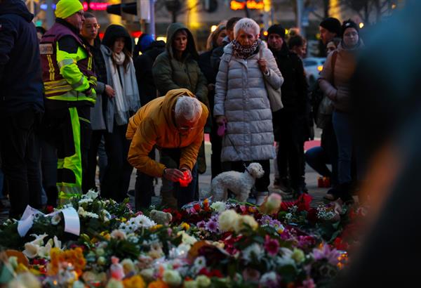 Magdeburgo (Alemania).- Varias personas se reúnen en el sitio oficial de duelo frente a la Iglesia de San Juan para presentar sus respetos tras un ataque con un vehículo en el mercado navideño, en Magdeburgo. 