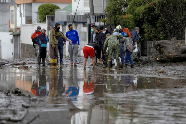 Vista de personas mientras ayudan en la labor de limpieza sobre el lodo ocasionado por las lluvias del día anterior, que afectó algunos barrios del oeste de la capital ecuatoriana, este 31 de enero de 2022.