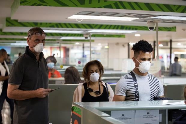 Viajeros usan tapabocas este viernes como protección ante la pandemia del coronavirus, mientras atraviesan migración en el Aeropuerto Internacional de Las Américas, en Santo Domingo.