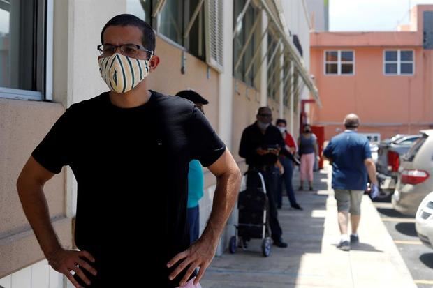 Un hombre usa una mascarilla de protección mientras espera en la fila en San Juan, Puerto Rico. 