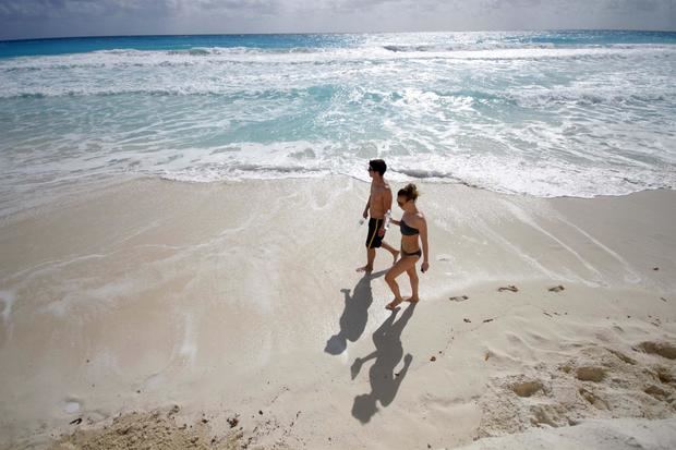 Fotografía de archivo de una pareja de turistas paseando por una playa de Cancún.