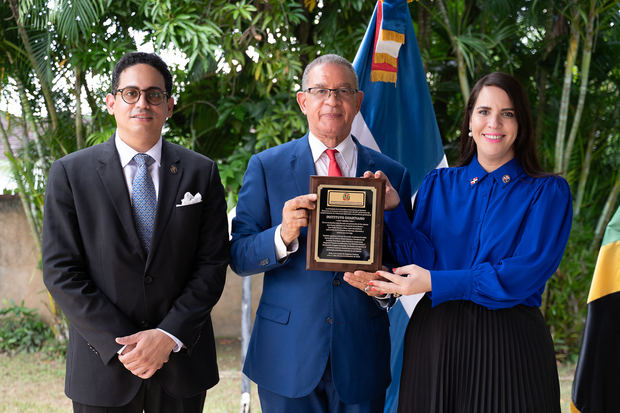 El presidente del Instituto Duartiano, Wilson Gómez Ramírez, recibe un reconocimiento en manos de la embajadora Angie Martínez y del ministro consejero y jefe adjunto de misión en Jamaica, Miguel Balaguer.