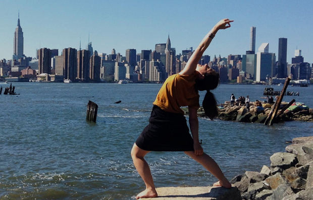 Postura del guerrero pacífico en yoga con la silueta de la ciudad de Nueva York de fondo.